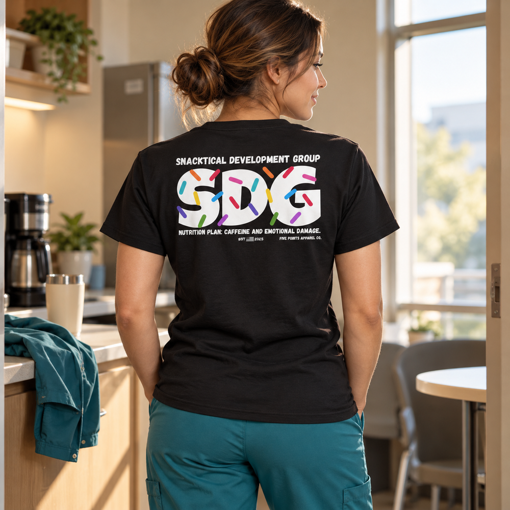 Healthcare worker wearing the black SNACKOLOGIST shirt with scrub pants during a break.